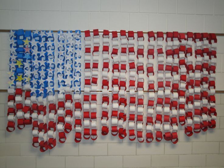 an american flag made out of red, white and blue ribbon hanging on a wall