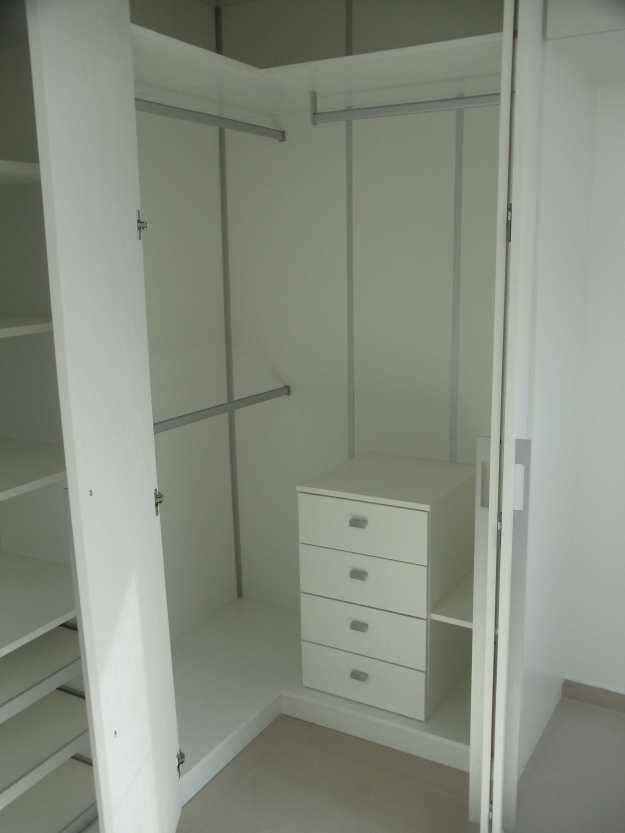 an empty closet with white shelves and drawers