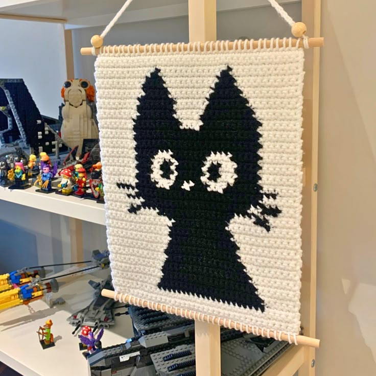 a black and white cat is hanging on a wall with legos in the background