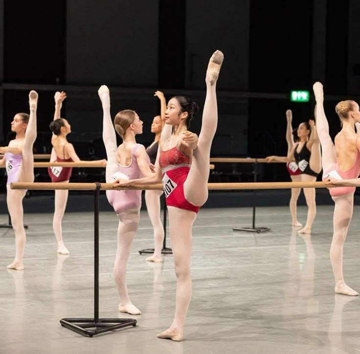 a group of ballerinas standing around each other in front of a wooden pole