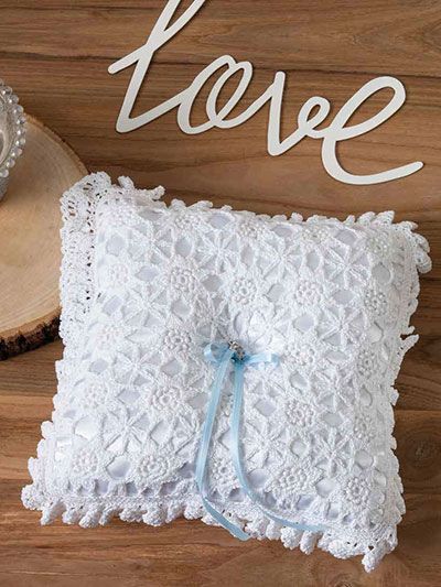 a white lace pillow sitting on top of a wooden table next to a cupcake