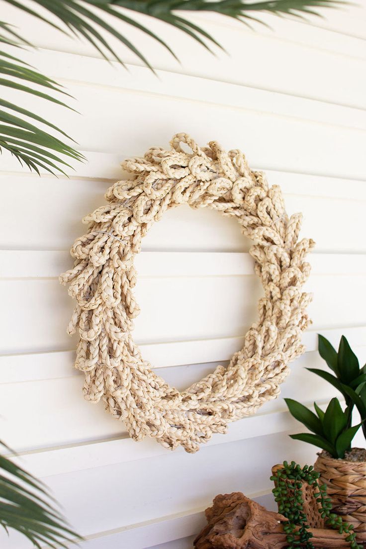 a rope wreath hanging on the wall next to a potted plant