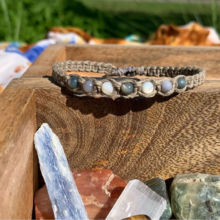 a close up of a bracelet on top of a wooden box next to rocks and crystals