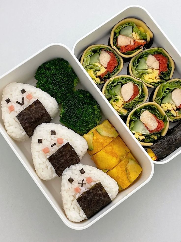 two trays filled with sushi and vegetables