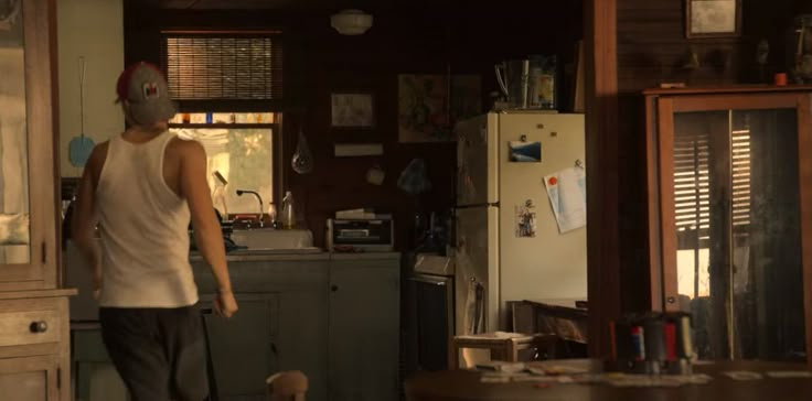 a man standing in a kitchen next to a refrigerator