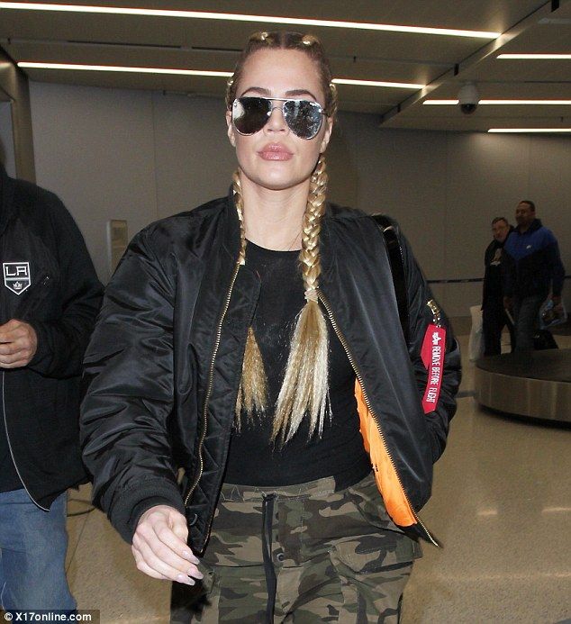 a woman in camouflage pants and sunglasses walking through an airport