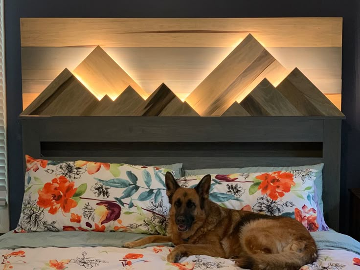 a german shepard dog laying on a bed in a bedroom with wood headboard and flowered bedspread