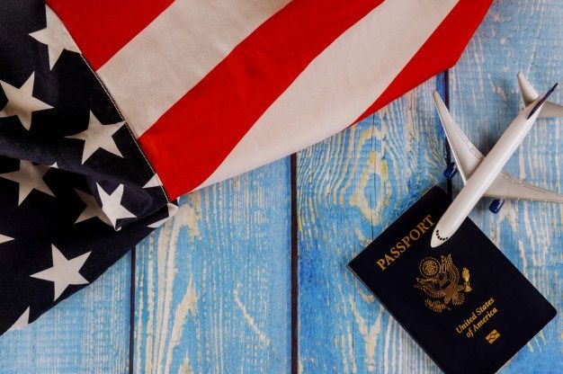 an american flag, passport and airplane on a blue wooden background