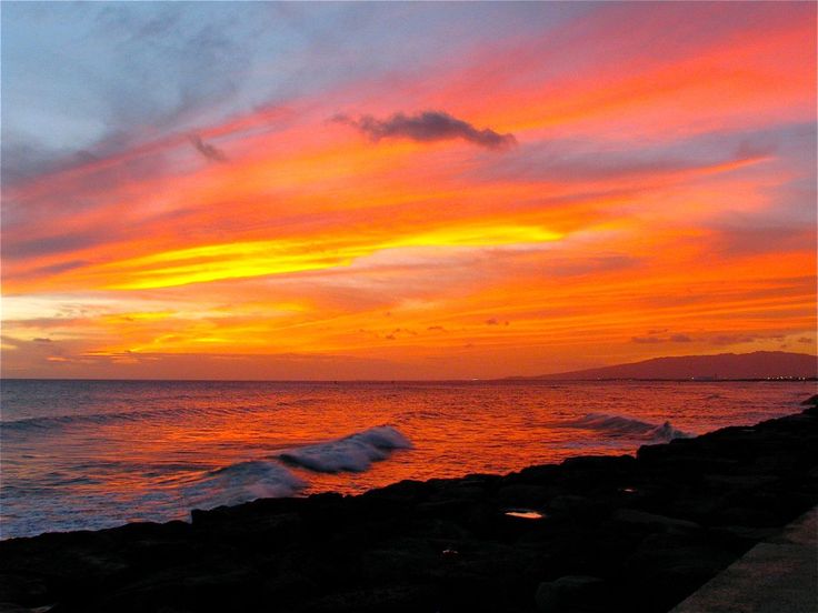 the sun is setting over the ocean with waves coming in