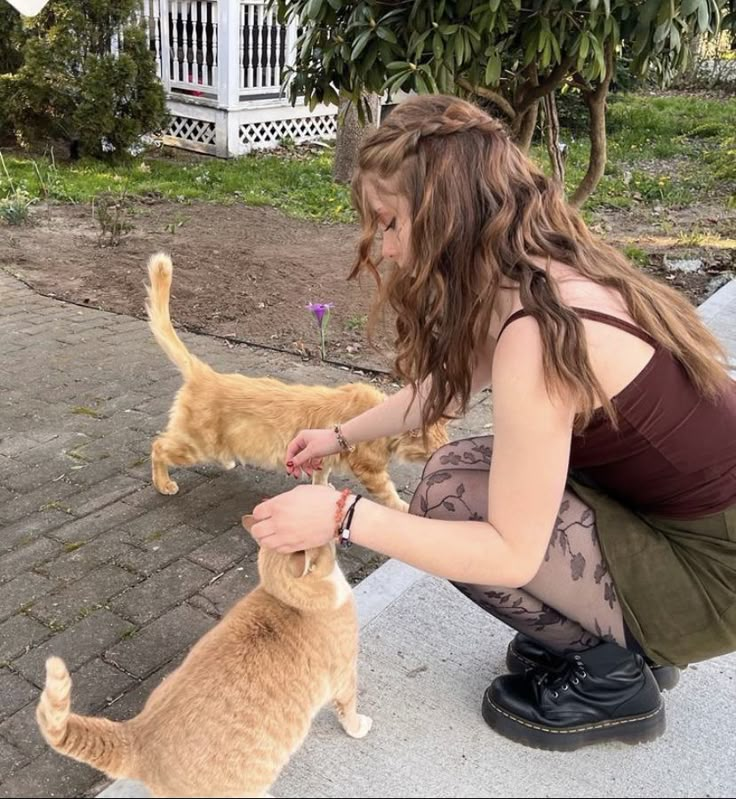 a woman kneeling down petting an orange cat