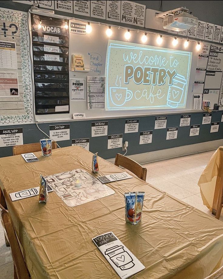 there is a table set up for a poetry night with posters on the wall behind it