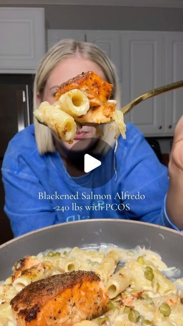 a woman is eating pasta with salmon and macaroni