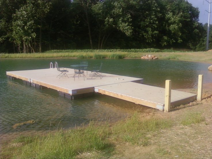 an empty dock sits in the middle of a body of water with trees in the background