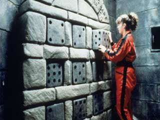 a woman standing in front of a wall made out of diced up pieces of stone