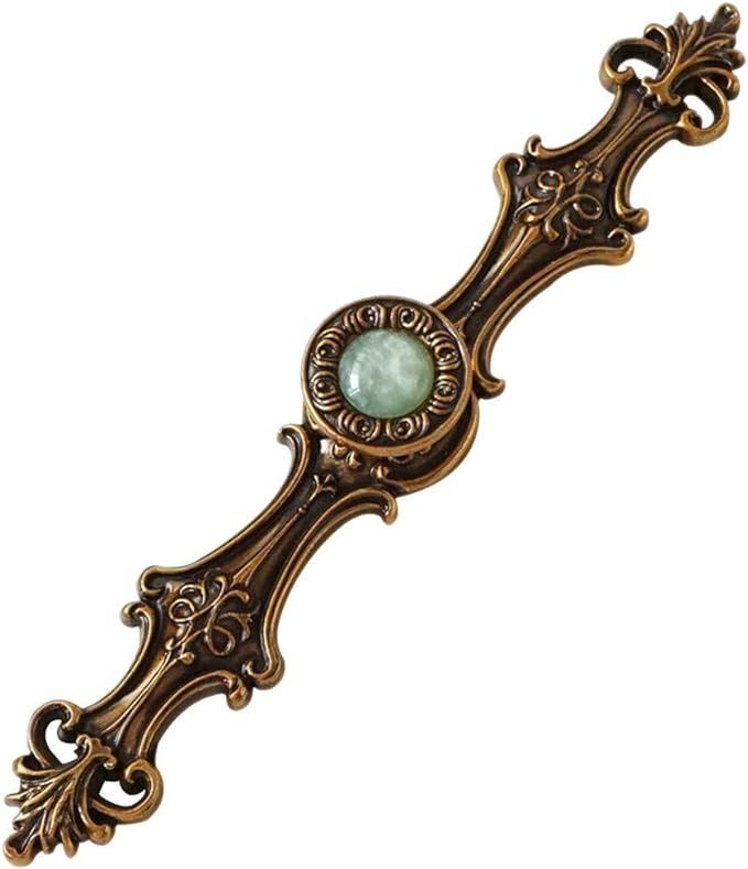 an ornate metal handle with a green stone in the center