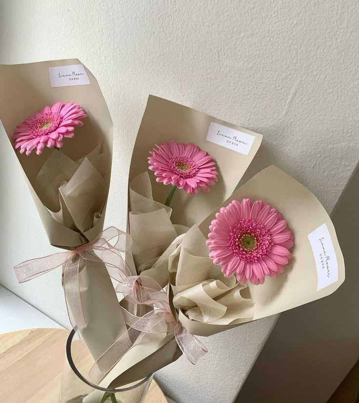 three pink flowers are in a vase on a table