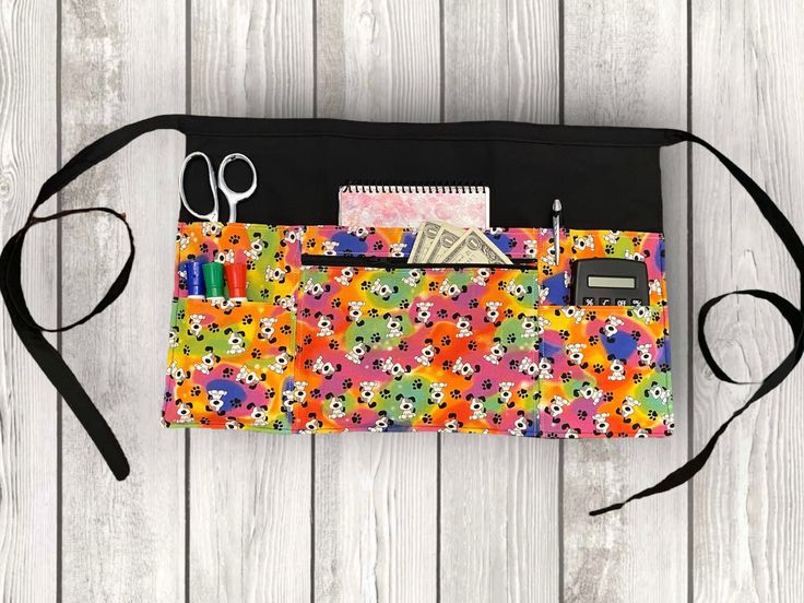 a multicolored purse with scissors and other items in it on a wooden surface