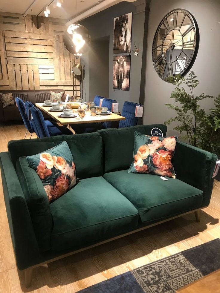 a green couch sitting in the middle of a living room next to a wooden table