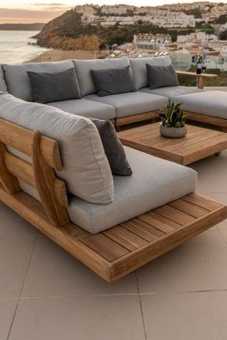 a couch and coffee table on a patio overlooking the ocean with city in the background