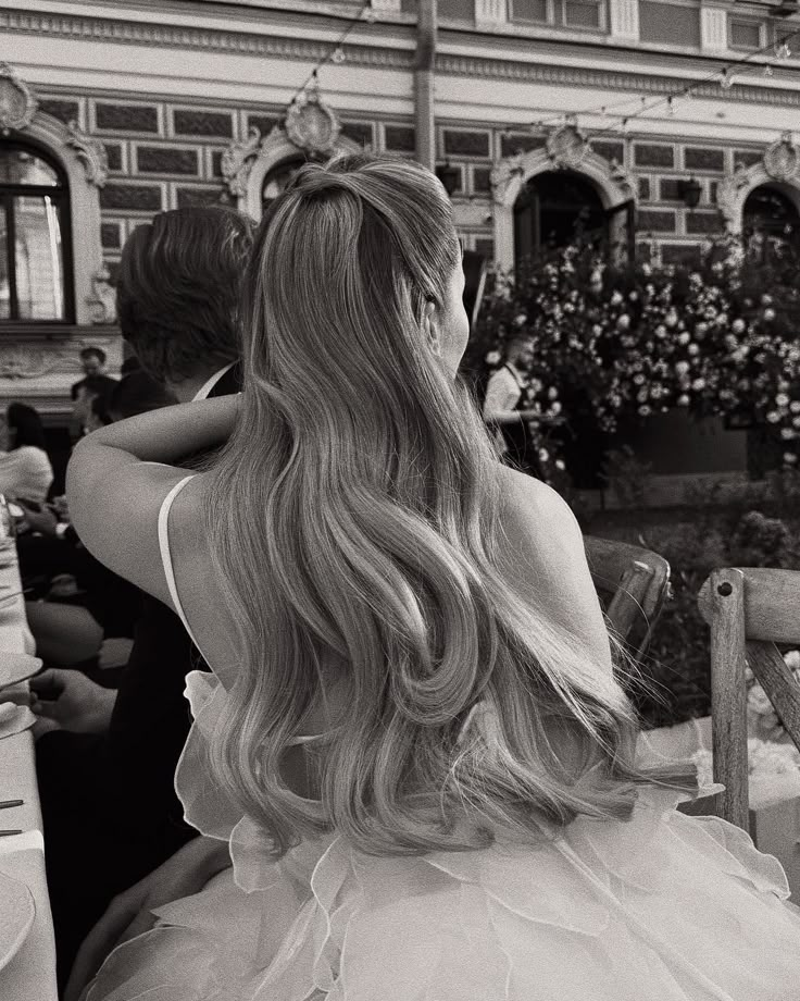 a woman sitting at a table with her back to the camera, wearing a wedding dress