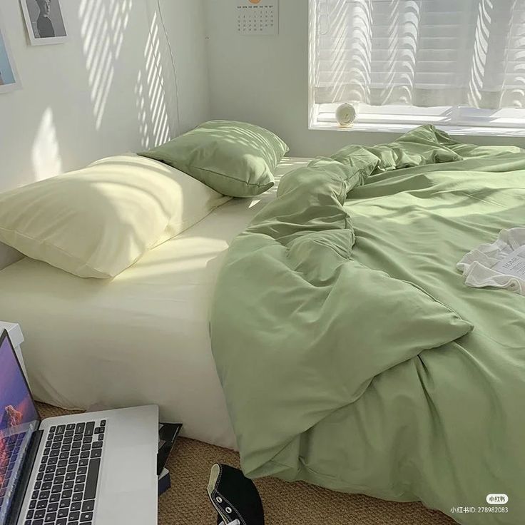 a laptop computer sitting on top of a bed next to pillows and blankets in a bedroom