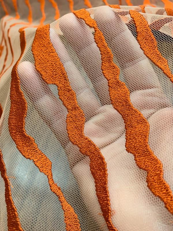 an orange and white fabric with wavy lines on the edges is shown in close up