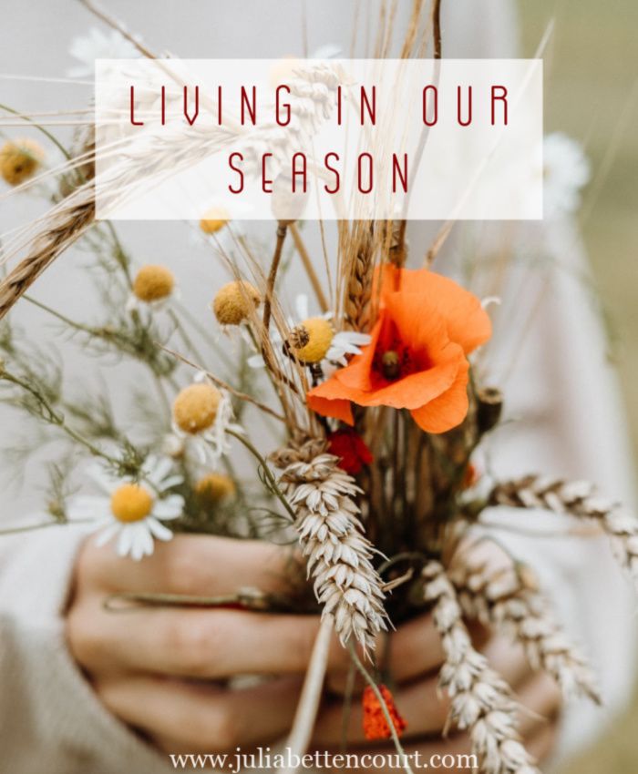 a person holding flowers and wheat stalks with the words living in our season on it