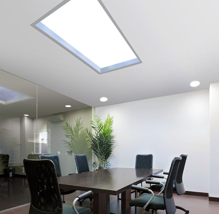 an empty conference room with a skylight above the table and black chairs around it