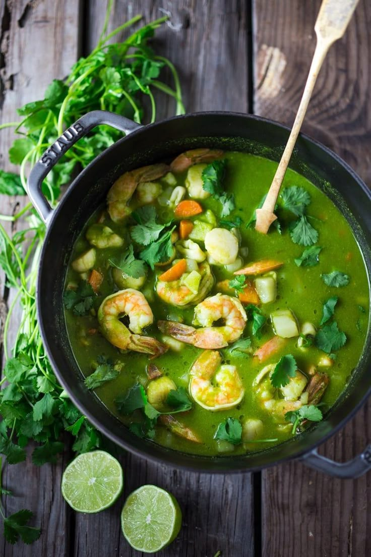 a pot filled with soup and garnished with shrimp, cilantro, and parsley