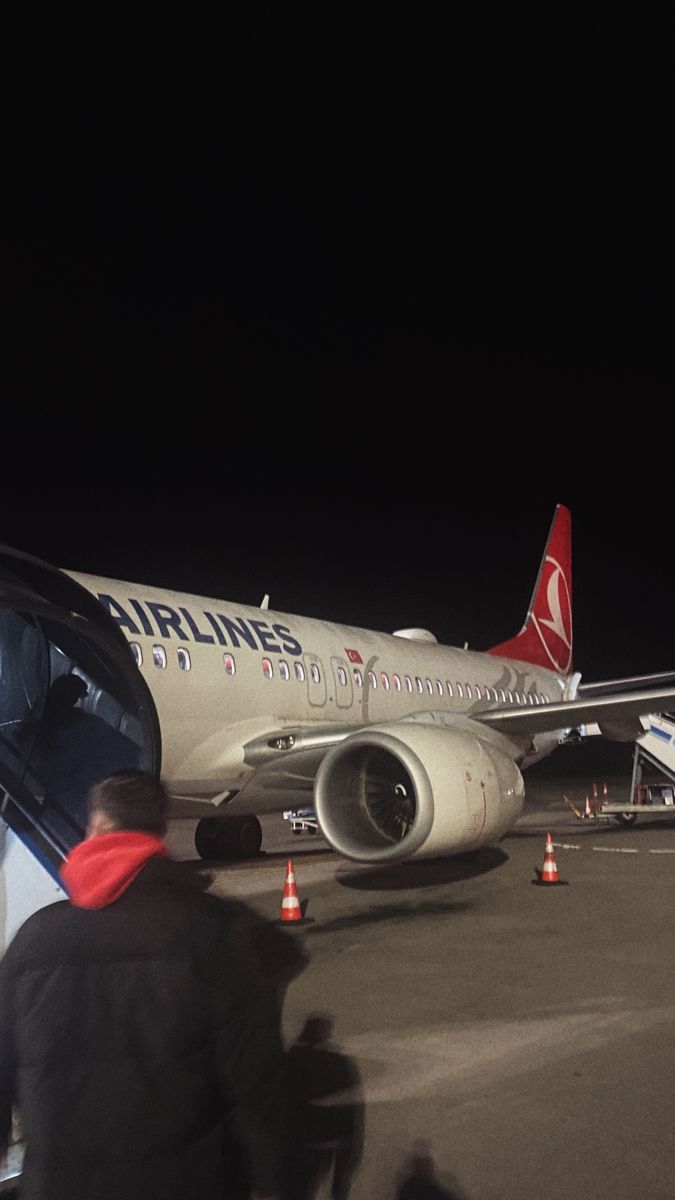 an airplane sitting on the tarmac at night with its door open and passengers boarding