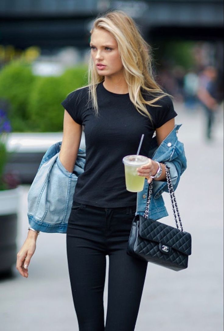 a woman walking down the street with a drink in her hand