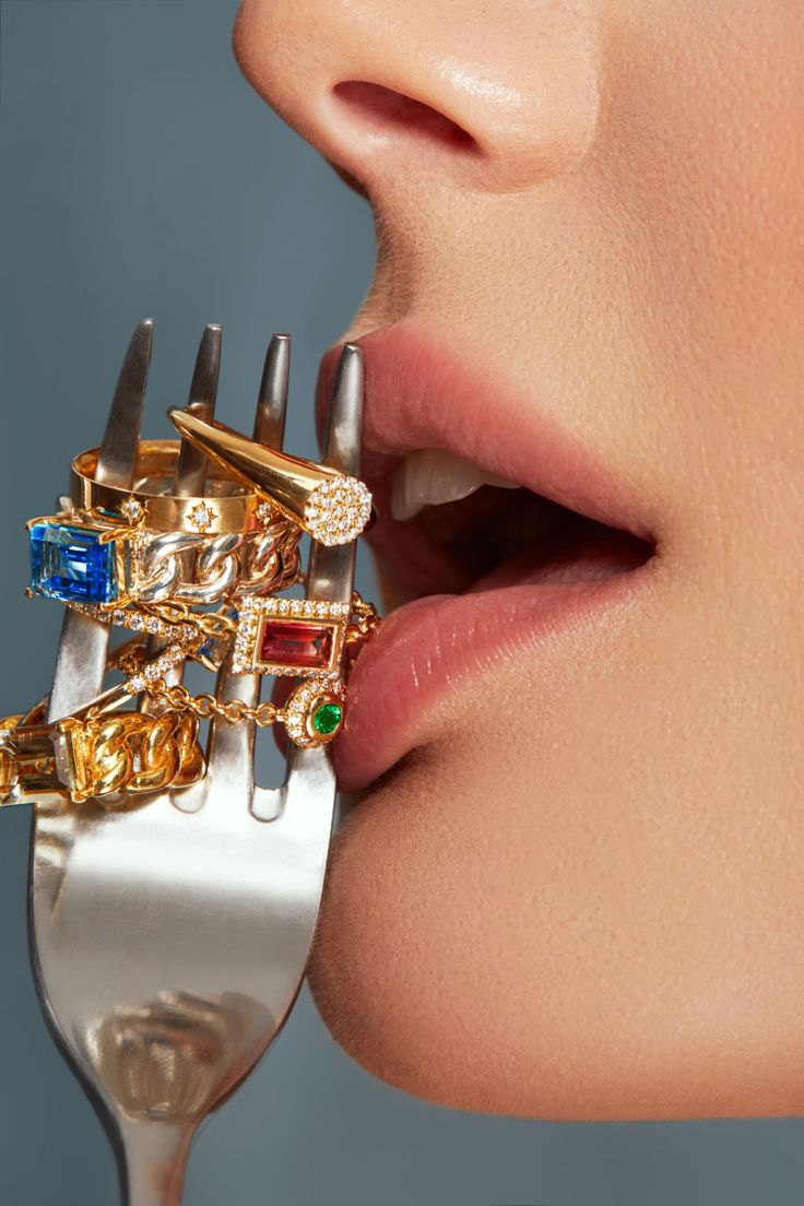 a close up of a person holding a fork with rings on it's fingers