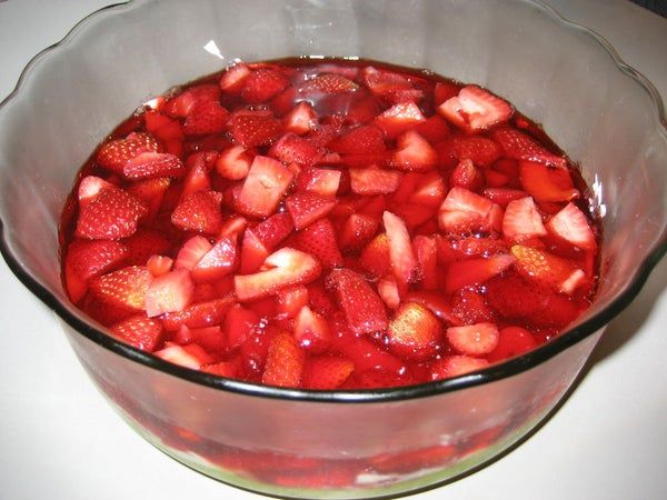 a bowl filled with sliced strawberries on top of a table