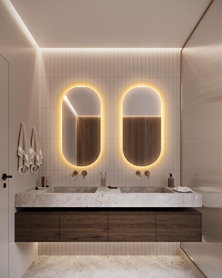 a bathroom with two sinks, mirrors and lights on the wall above it's counter