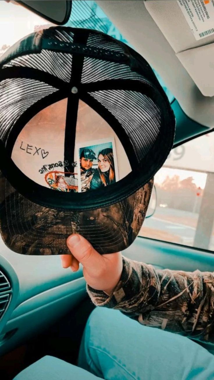 a person sitting in a car holding up a hat