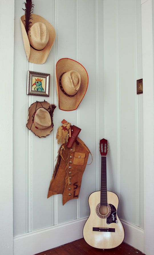 there is a guitar, hat and other items on the wall in this room with white paneling