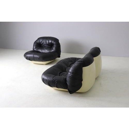 two black and white leather chairs sitting next to each other on top of a floor