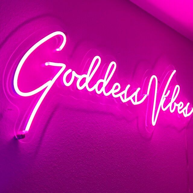 a neon sign that says goddess records on the side of a wall in a room