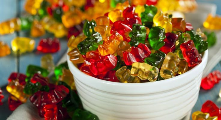 colorful gummy bears are in a white bowl