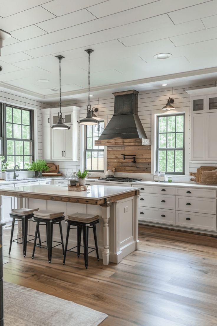 a large kitchen with white cabinets and wooden floors