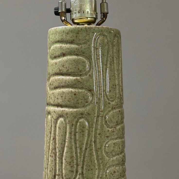 a green vase with a lighter on top of it