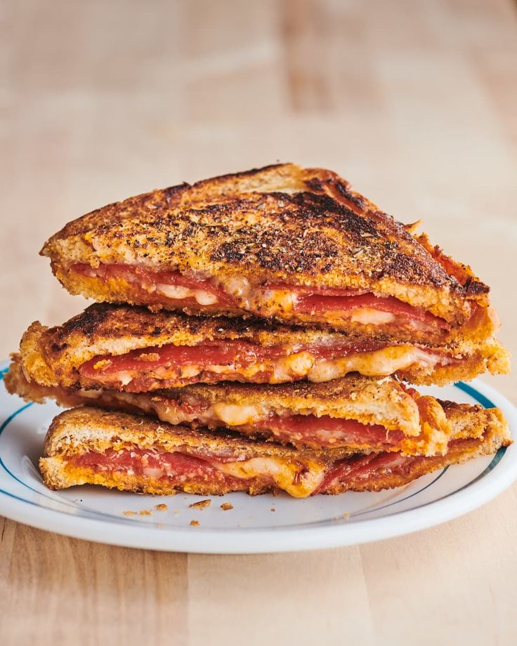 two grilled sandwiches stacked on top of each other with cheese and bacon toppings