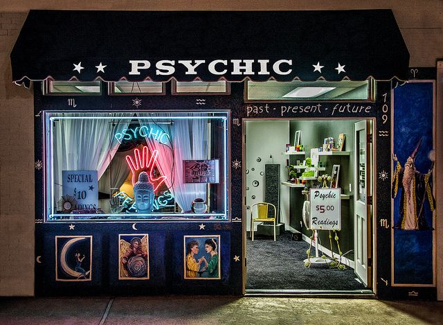 the psychic store front is lit up with neon lights and posters on it's windows