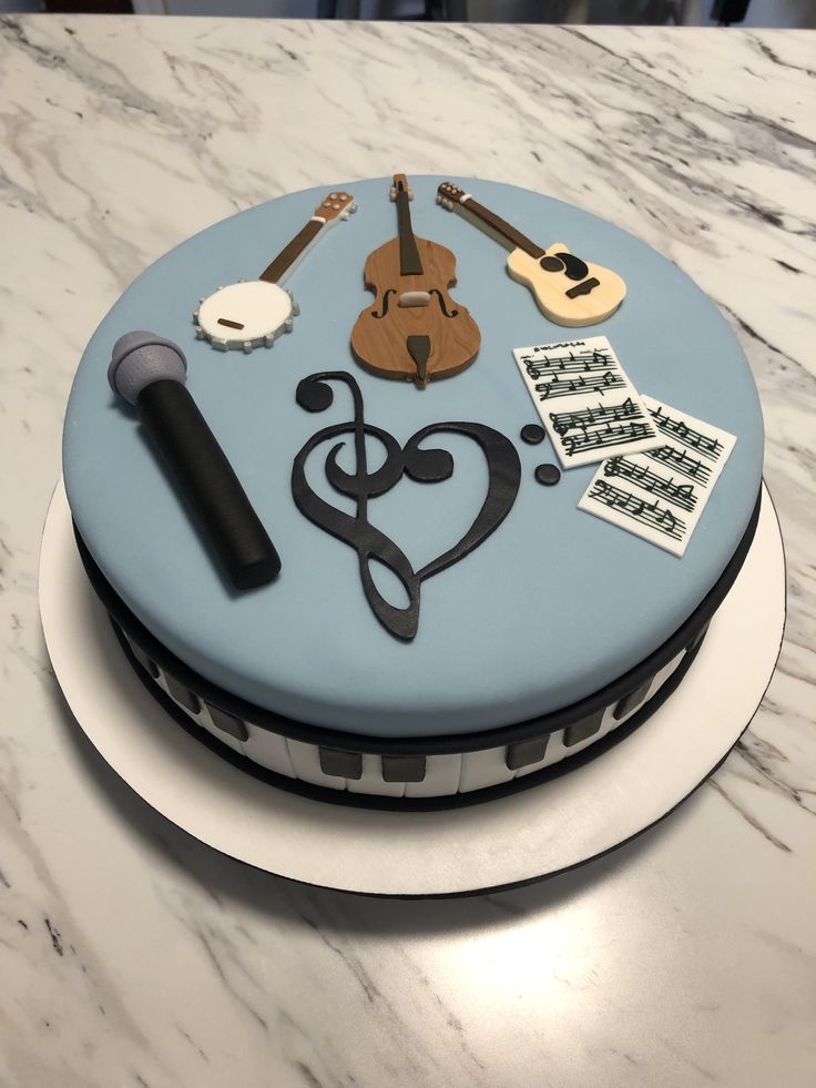 a cake with musical instruments on it sitting on top of a marble countertop next to sheet music