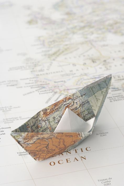 an origami boat sitting on top of a map