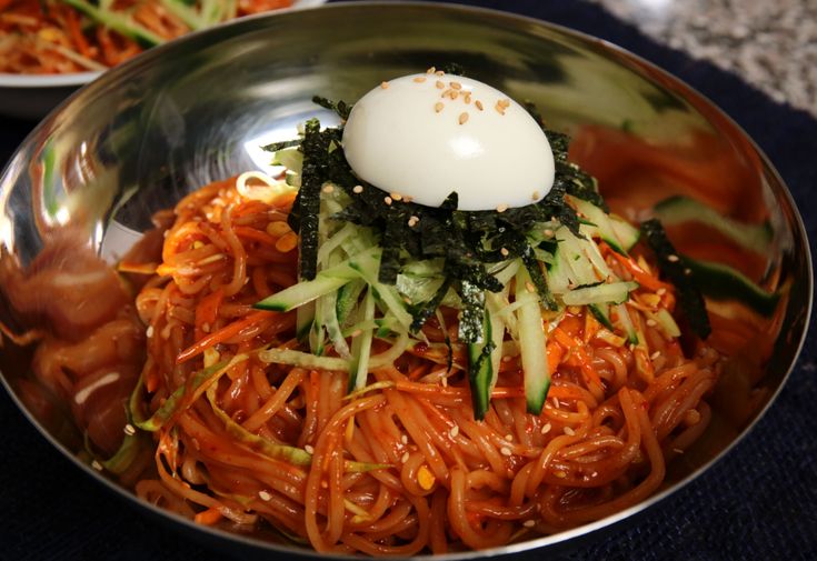 a bowl filled with noodles, vegetables and an egg on top of the food in it