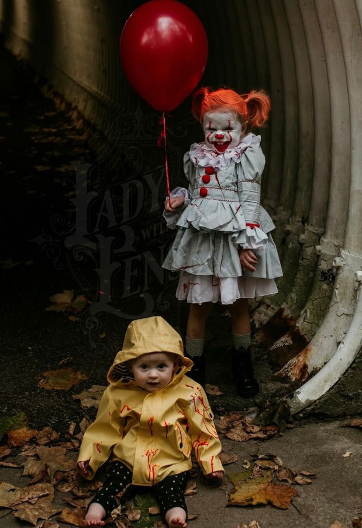 two children dressed up as clowns with red balloons