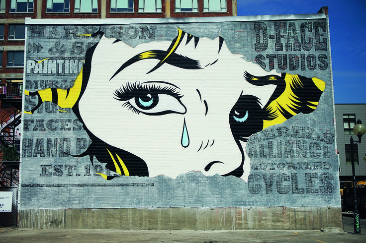 a large mural on the side of a building depicting a woman's face with tears