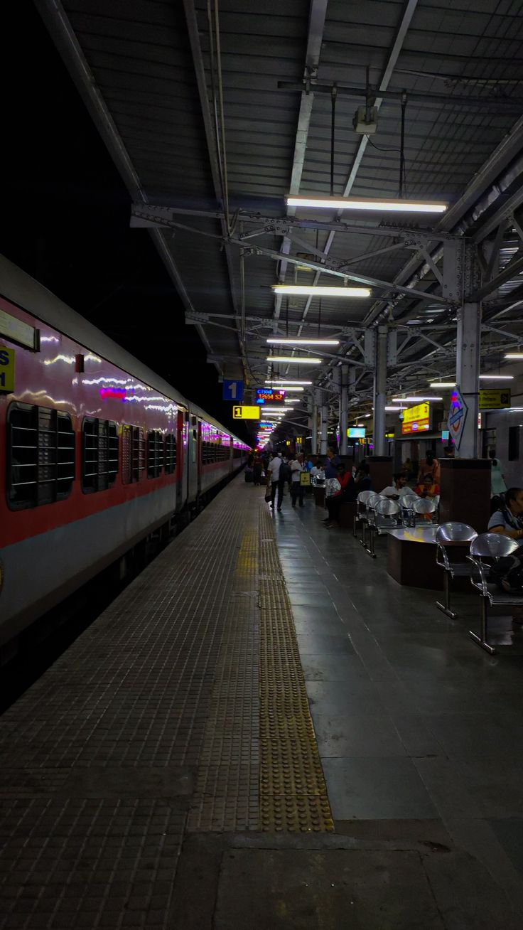 people are sitting on benches near a train at the station while it's stopped