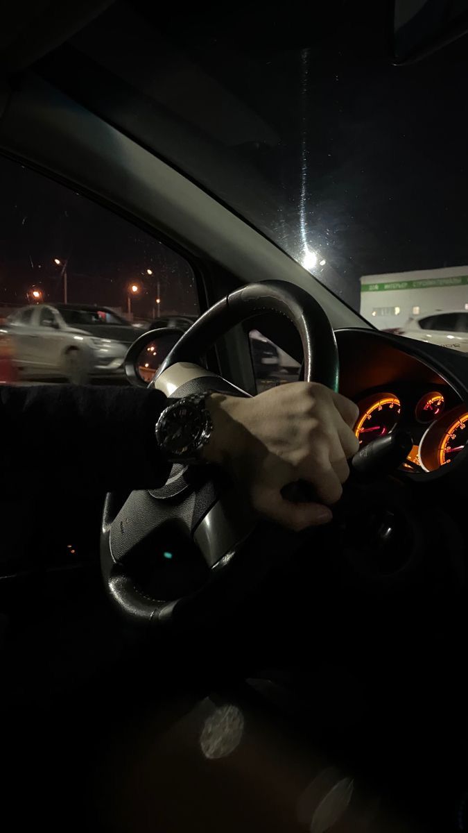 a person driving a car at night with their hand on the steering wheel and dashboard lights